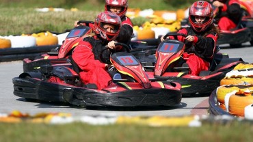 Ludzie w kombinezonach jadą gokartami w Parku Rozrywki