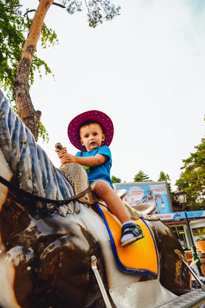Chłopiec w kowbojskim kapeluszu na zabawkowym koniu