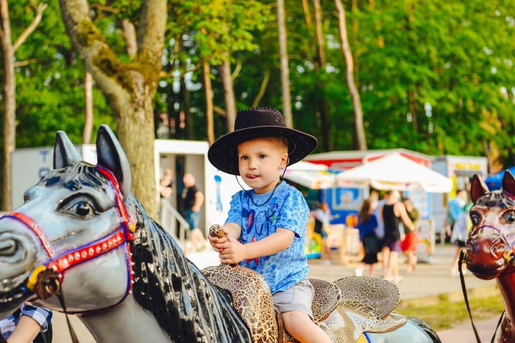 Szczęśliwe dziecko w kapeluszu na zabawkowym koniu