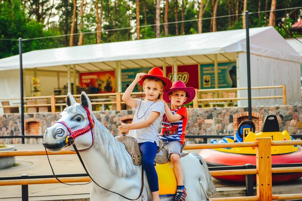 Wesołe dzieci w kowbojskich kapeluszach na zabawkowym koniu