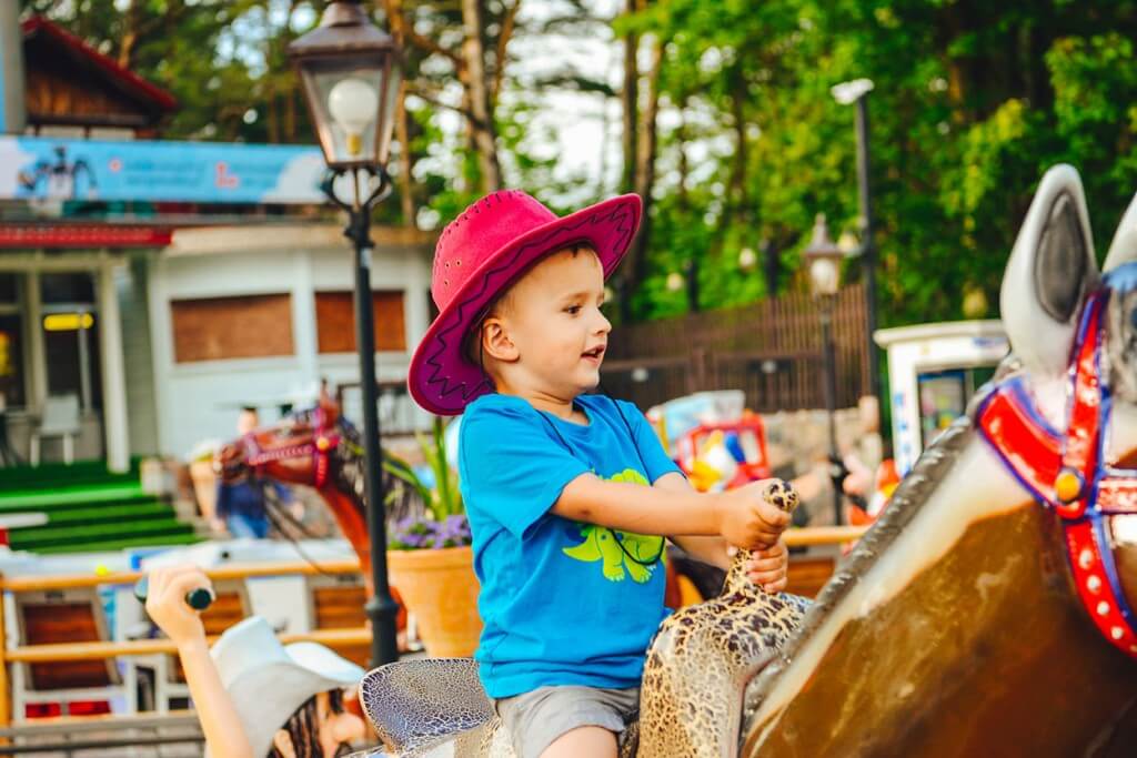 Uśmiechnięte dziecko w kapeluszu na zabawkowym koniu