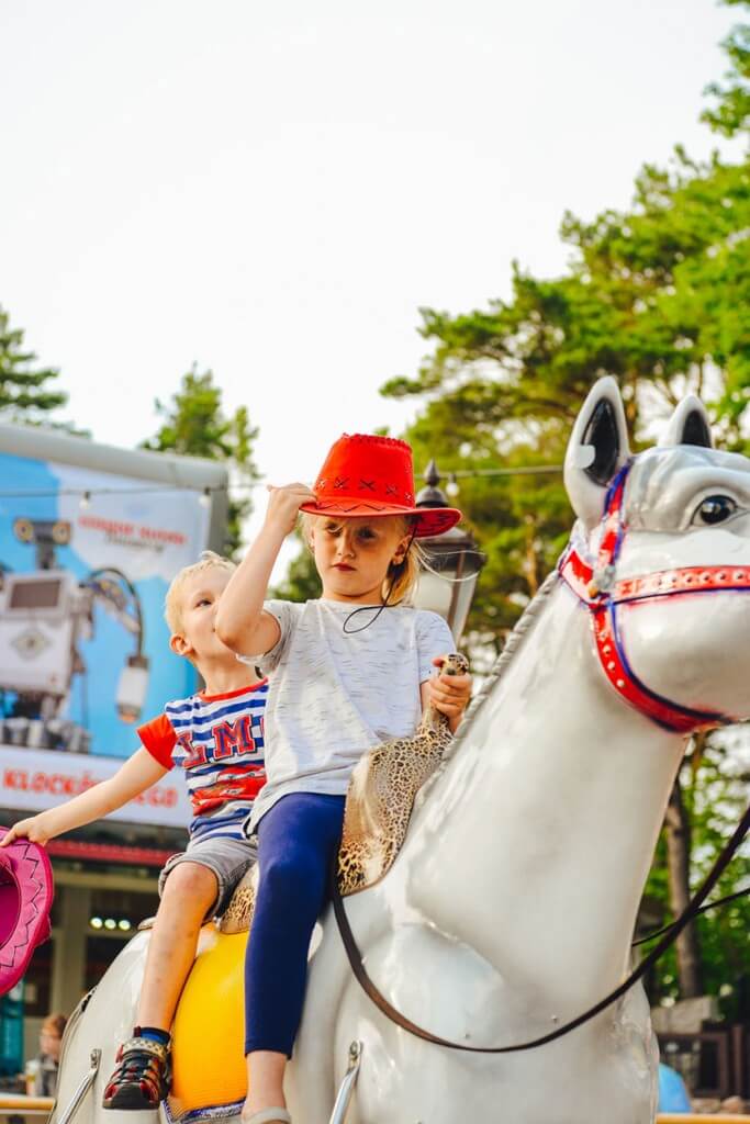 Radosne dzieci w kowbojskich kapeluszach na zabawkowych koniach